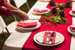 Mesa navideña con platos decorados y mano sirviendo comida