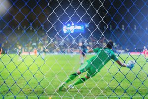 Portero de fútbol lanzándose a parar un balón en un partido